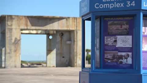 Medium shot of a blue exhibit kiosk near concrete structures.