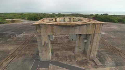 Aerial view of a weathered concrete structure on a paved area.