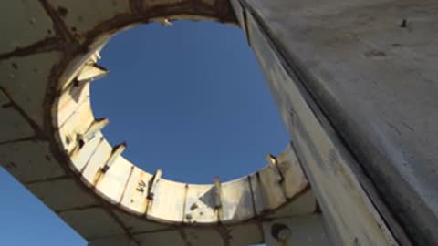 Low angle shot looking up through a round opening in a concrete structure.