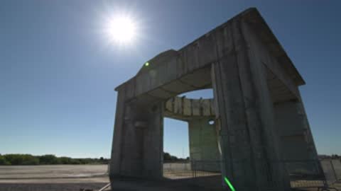 Low angle shot of a concrete structure with the sun shining brightly above.