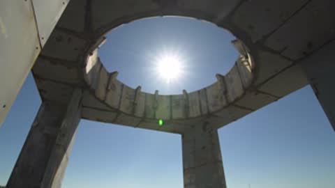 Wide low angle shot of a concrete structure framing the sun.