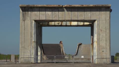 Medium shot through a concrete structure towards a weathered wall.
