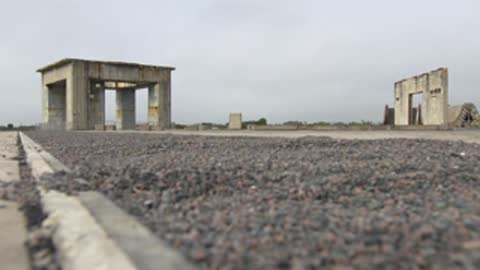 Low angle wide shot of concrete structures on a gravel field.