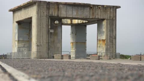 Medium shot of a concrete structure viewed across a gravel area.
