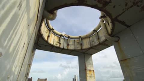Looking up at the circular opening in the concrete structure roof against the sky