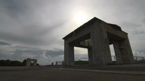 Low angle tracking shot of the Launch Complex 34 structure with sun breaking through clouds