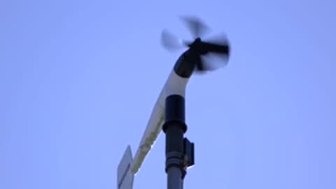 rotating anemometer measuring wind speed against a bright blue sky
