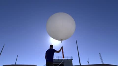man preparing to release a weather balloon against bright sunlight