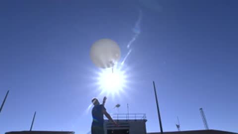 man releasing a weather balloon that ascends quickly into the sky