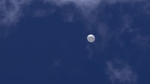 weather balloon drifting high in the sky through thin clouds