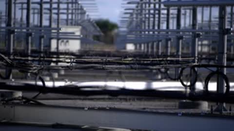 Close-up tracking shot moving through layers of metal framework and horizontal cables.