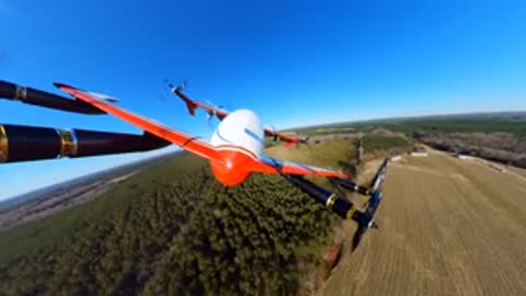 Forward aerial view from the flying aircraft over a wooded rural landscape.