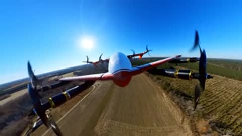 Frontal view from the aircraft as it flies over a road and field.