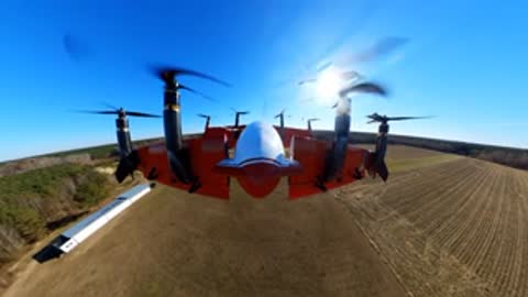A drone hovering in the air above an open field.