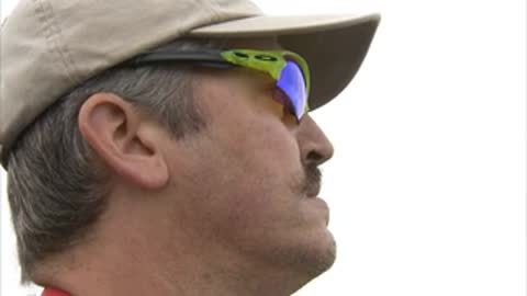 A person wearing a hat and sunglasses watching intently.