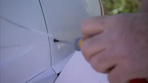 Hands use a screwdriver to secure a component on the aircraft.