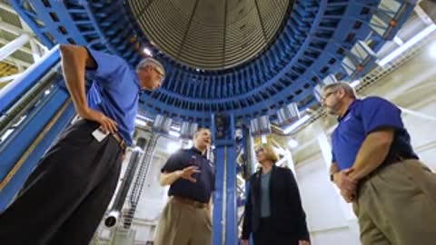 People looking up at the interior of a large circular structure indoors.