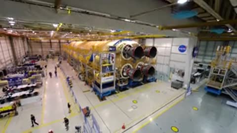 Wide overhead shot of workers inside a large warehouse building rockets.