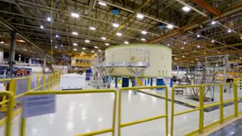 Wide shot of a clean industrial assembly floor with machinery and yellow safety railings.