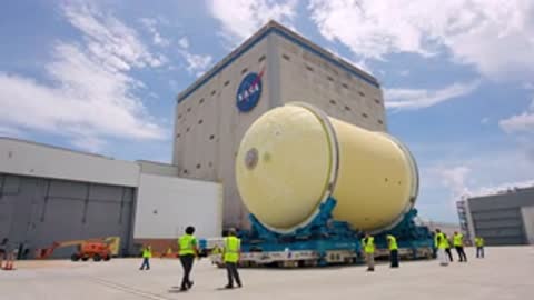 Medium tracking shot of a large cylindrical tank being transported outside on a trailer.