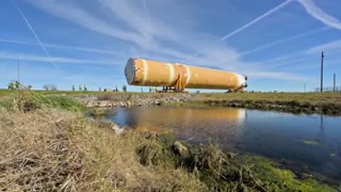 Rocket stage transport moving along path near water channel