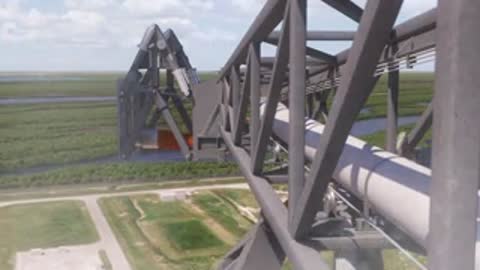 Wide animation looking down from a gantry structure toward a launch site, period details.