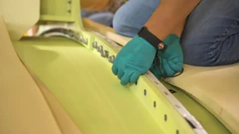 Gloved hands installing metal fasteners on a rocket component flange.