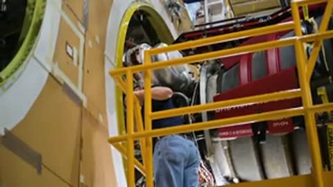Close-up of workers inspecting engine components inside an assembly building.