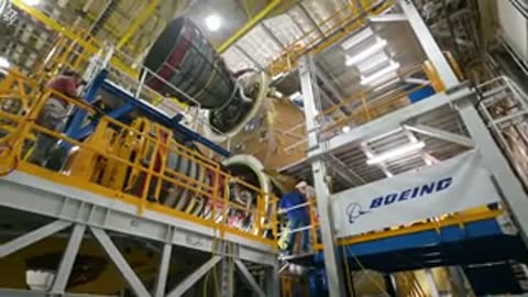 Low angle view of workers assembling rocket engines inside high bay.