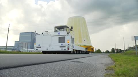 Launch vehicle stage adapter transported on flatbed vehicle outdoors.