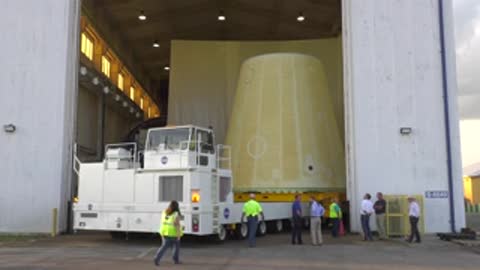 Launch vehicle stage adapter being moved into warehouse by transport vehicle.