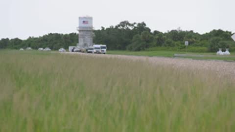 wide shot of grassy field with blurred transport in distance