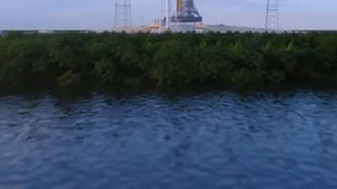 aerial view tracking over marshland towards rocket launch pad
