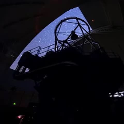 Silhouette of an operator inside a telescope dome looking at a projected star map.