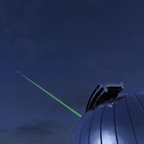 Observatory dome pointing a green laser beam into the night sky.