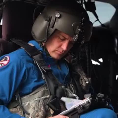 Astronaut in helmet sitting in a helicopter cockpit, adjusting equipment.