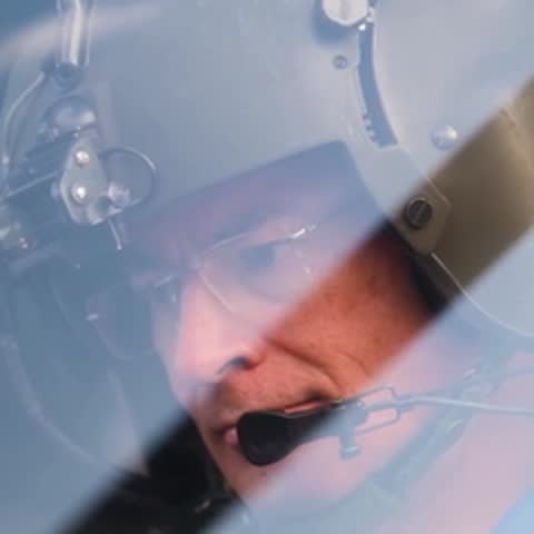 Close-up of an astronaut's face inside a helicopter helmet, looking down.