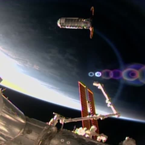 Spacecraft orbiting above Earth with a mechanical arm visible in frame.