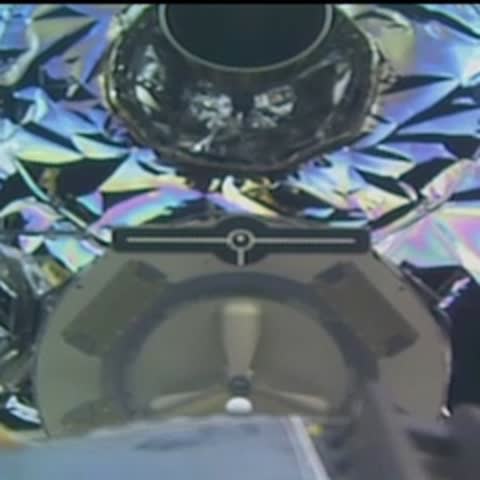 View from inside spacecraft looking out at a reflective surface and starry space.