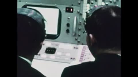 Close-up of personnel looking at a monitor and console interface