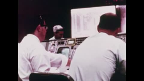 Medium shot from behind of two operators facing large display screens
