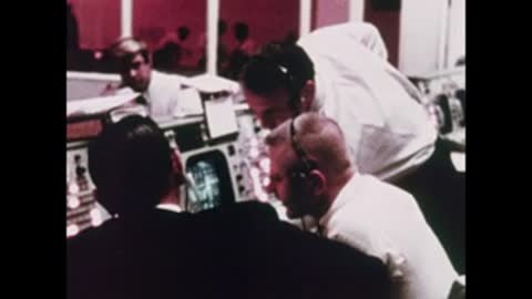 Medium shot of operators collaborating around a lit radar console screen