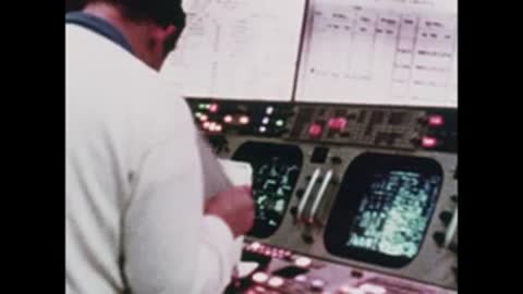 Medium shot of an operator reviewing documents next to active radar displays