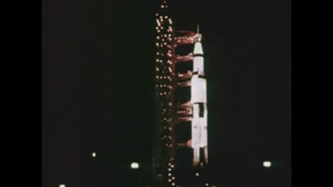 Night shot of a Saturn rocket standing tall on the launch pad structure