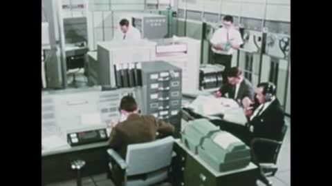 engineers working with computers and data printers in room