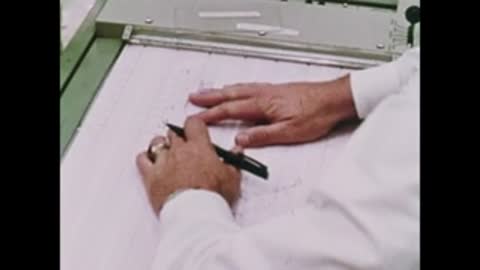 person writing on paper chart with stylus in control room