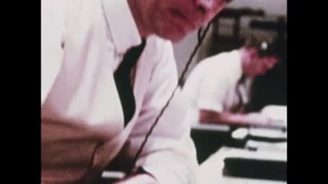A montage of mission control personnel working at their desks and consoles.