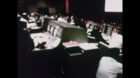 A wide shot of the dimly lit Mission Control room with glowing consoles.