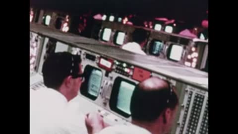 Medium shot of technicians working at computer consoles in Mission Control