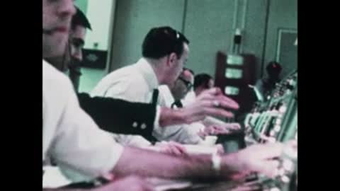 Medium shot of operators in white shirts working at control room consoles